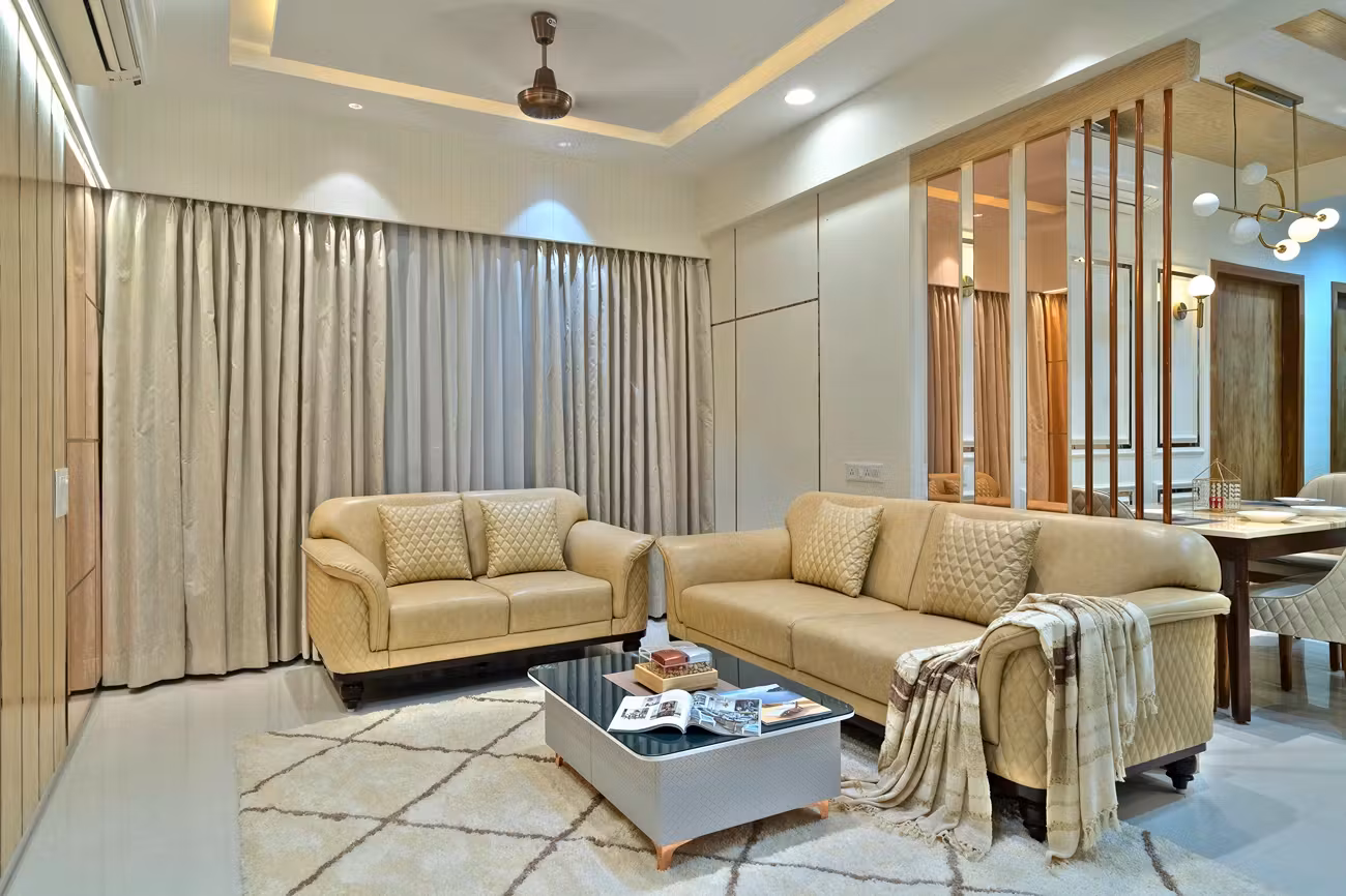 Grand living room with beige leather sofas, rose gold wall trim, and a designer marble-top center table at Shyam Sanvi.