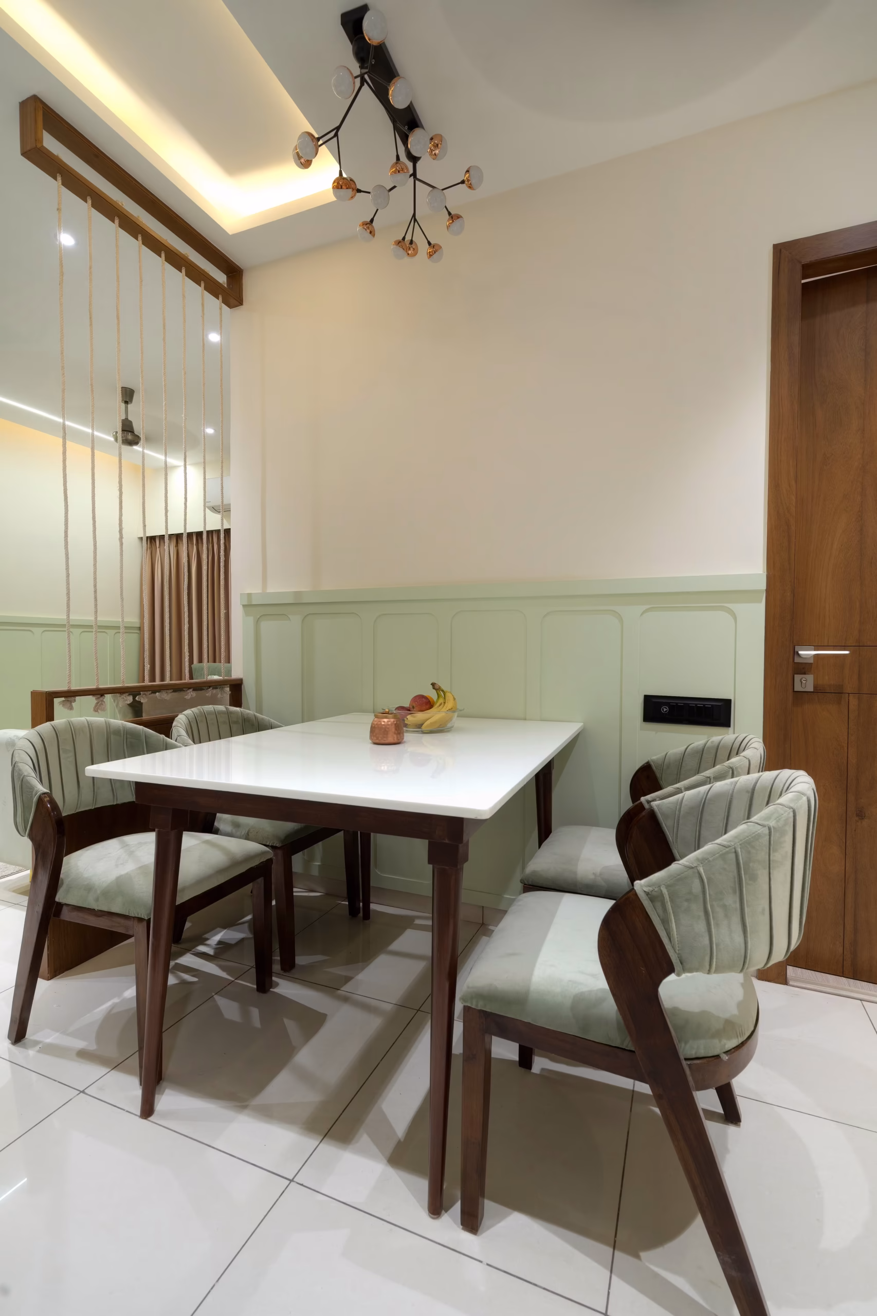 Elegant dining space featuring a white marble-top table, upholstered chairs, and decorative vertical string partitions