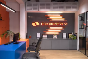 Modern office reception area for Carecay Vastral featuring orange brand signage and sleek blue desk.